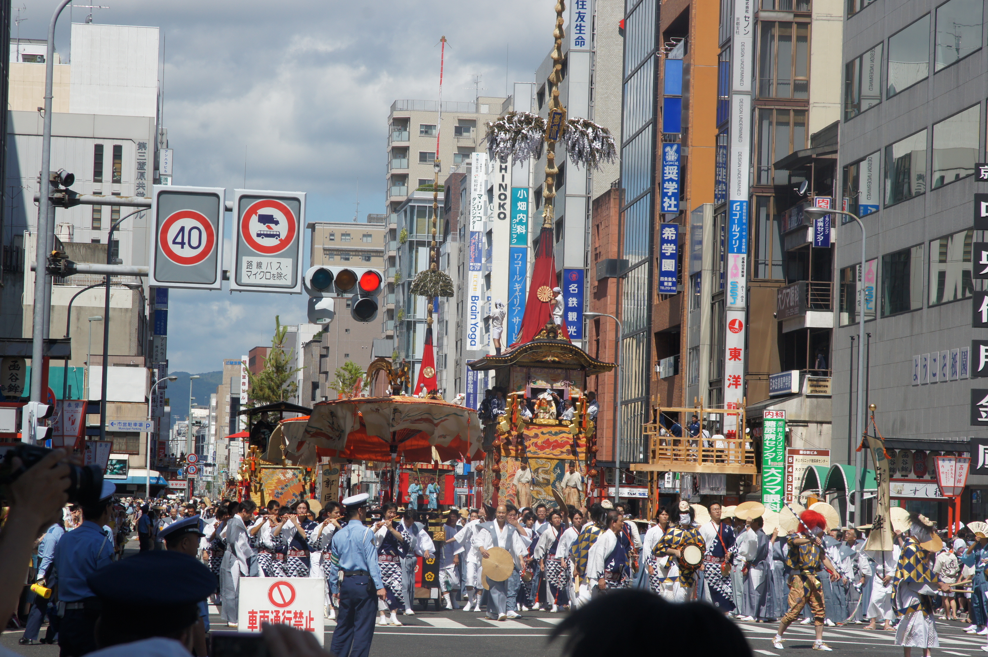 A towering wooden Yamaboko float decorated with tapestries being hauled through the narrow streets of central Kyoto during the Gion Matsuri procession
