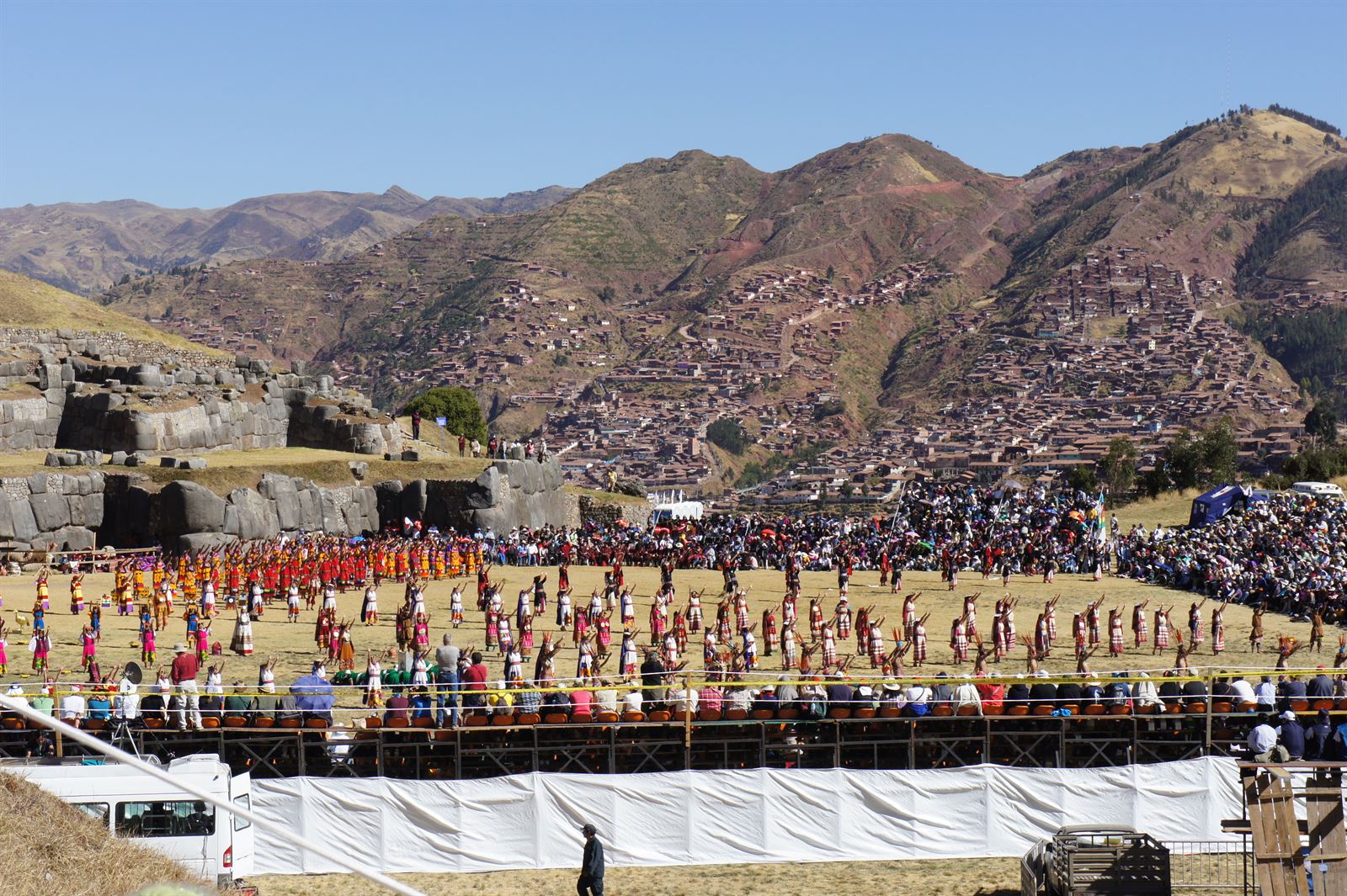 Costumed performers in red and gold Inca dress during the Inti Raymi ceremony on the esplanade below the stone walls of Sacsayhuaman in Cusco